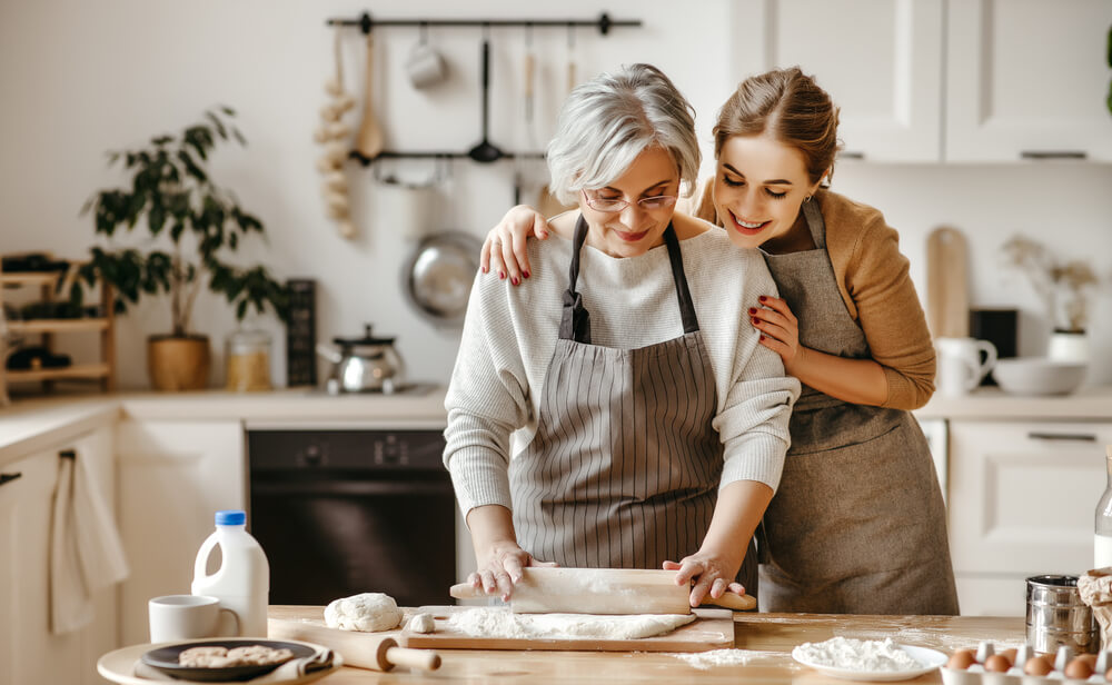 Mother and daughter rolling out biscuit dough in kitchen