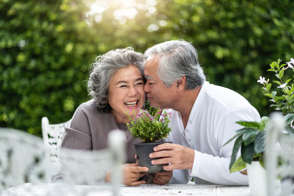 Elderly couple with gray hair holding a plant outdoors