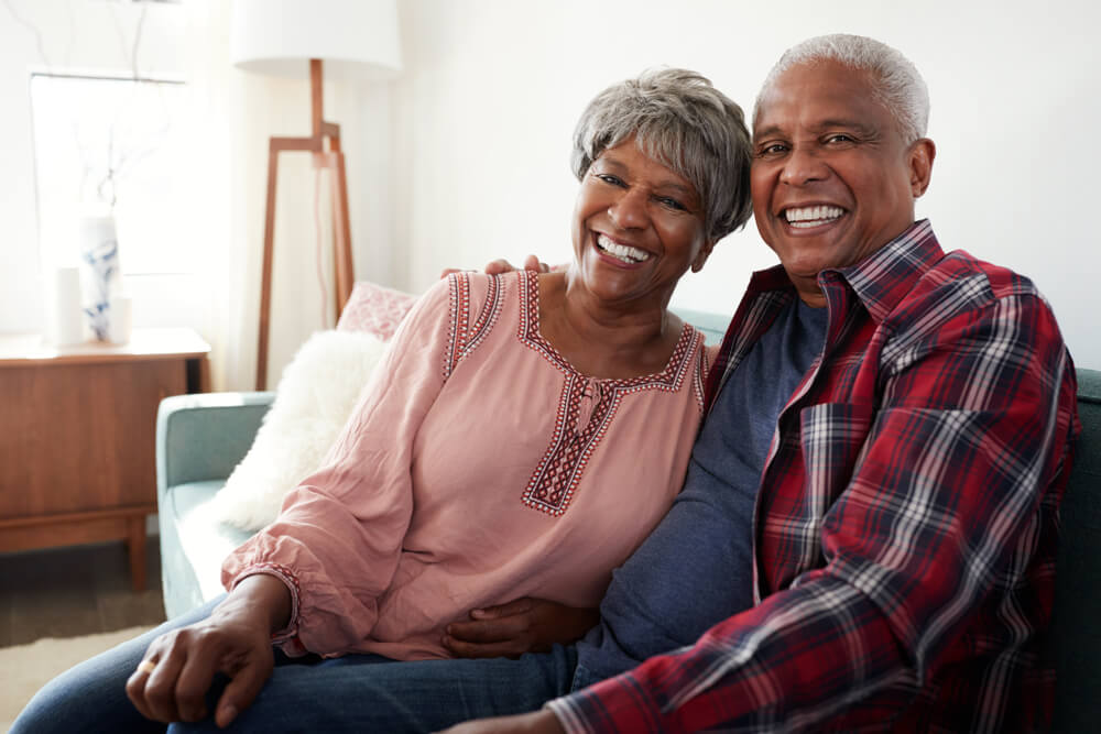 Couple in their 60s sitting on couch together and smiling