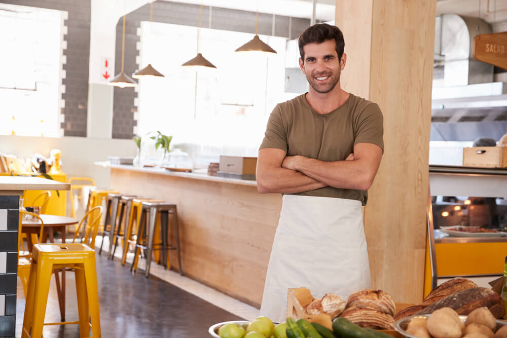 Man in his 30s wearing an apron in his cafe