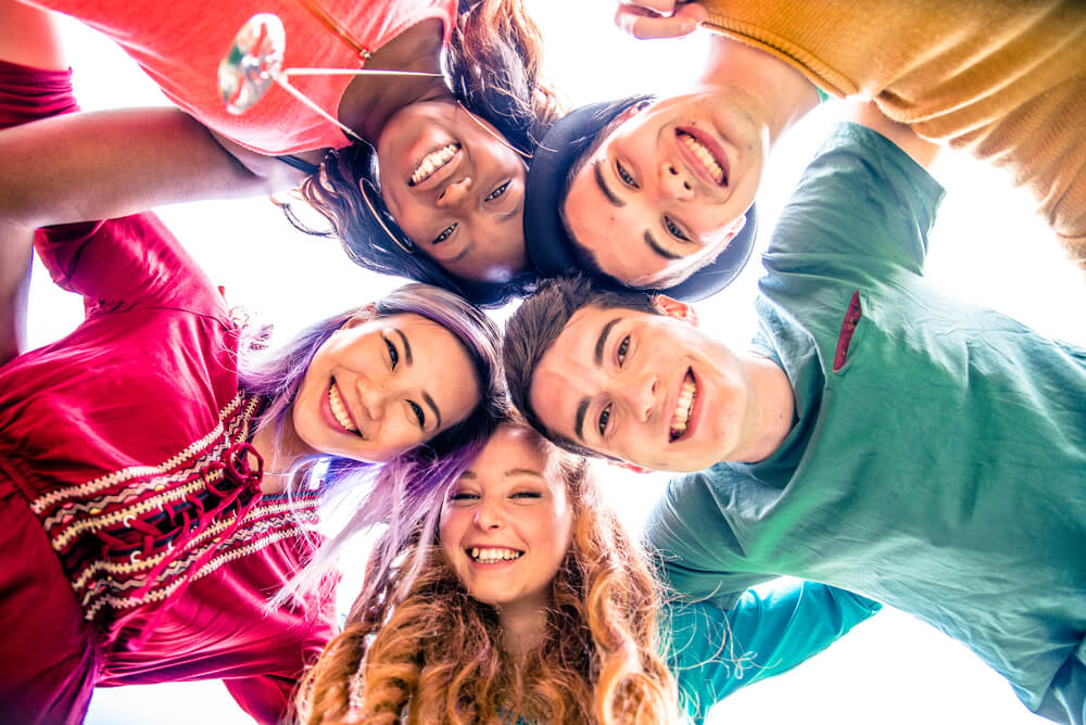 Teenagers in bright colors in a circle and smiling