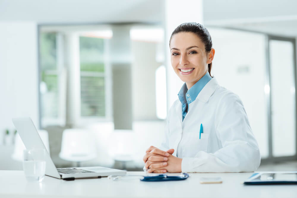 Young doctor smiling from behind desk