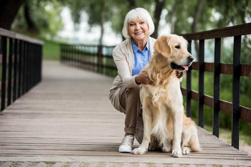 Senior woman with dog on a wooden bridge walkway