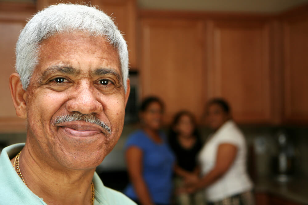 Closeup of senior man with family blurred in background