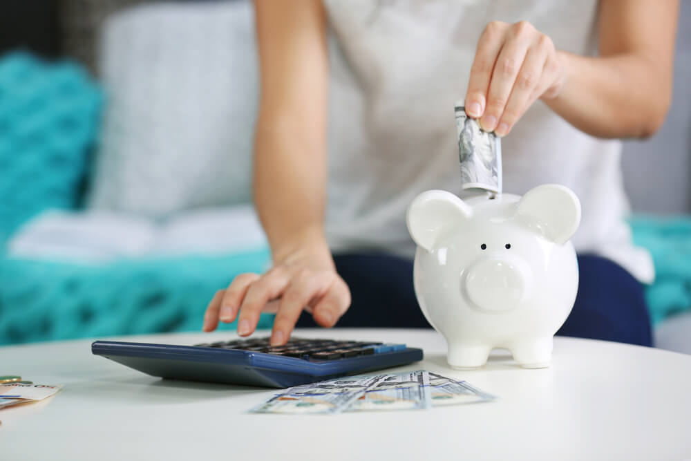 Woman putting money in a white piggy bank