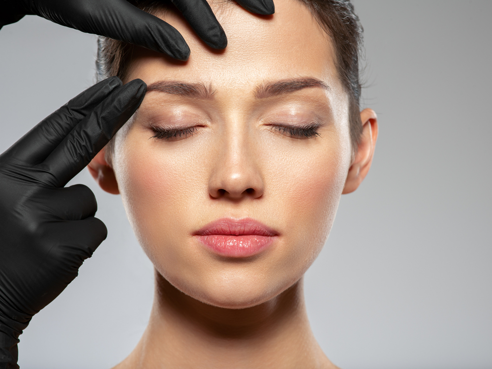 woman's face being assessed by medical professional with gloves on