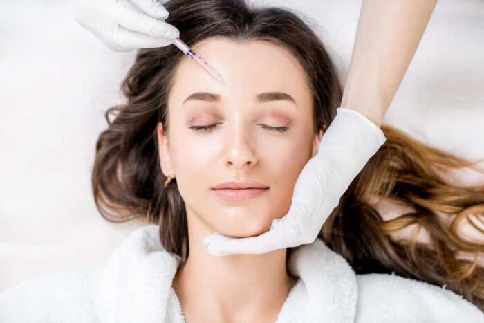 young woman getting a botox injection in her forhead